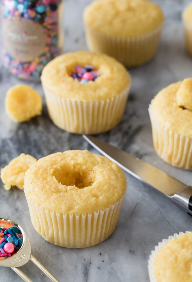 Carving a hole in the center of vanilla cupcakes to make Pinata Cupcakes