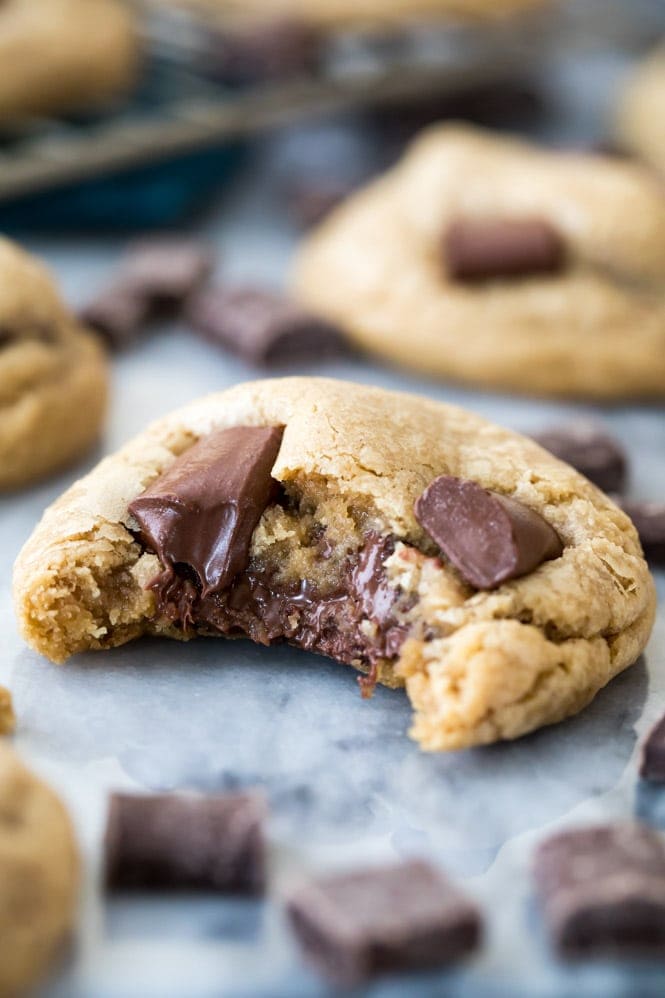 A thick, soft, chewy chocolate chip cream cheese cookie hot out of the oven with a bite taken out