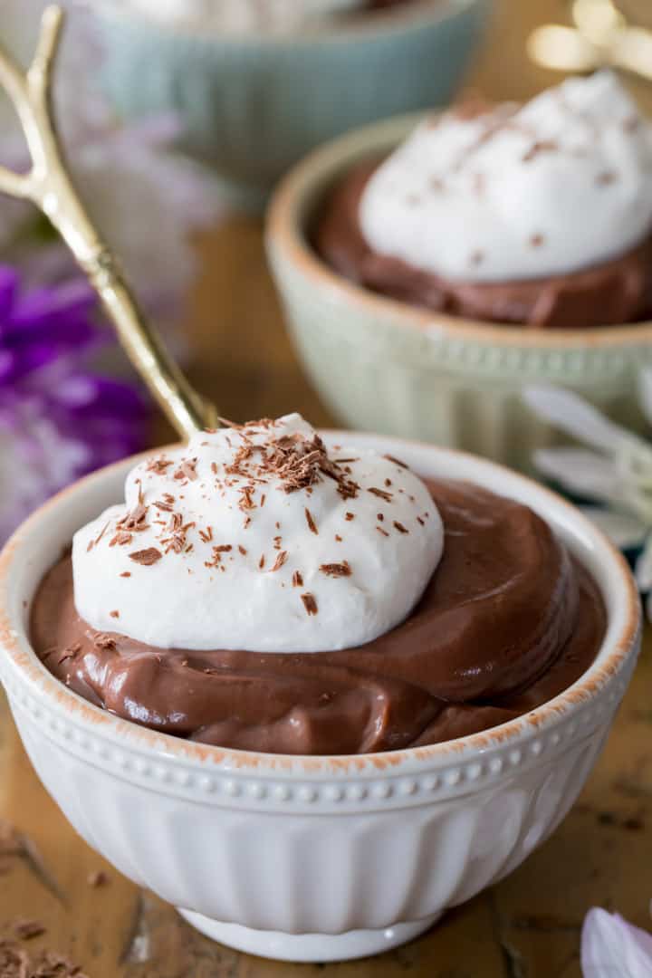 A bowl of homemade chocolate pudding topped with whipped cream and chocolate flakes