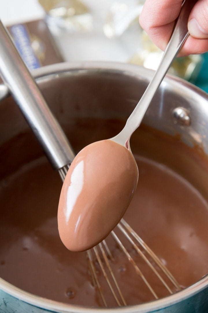 Chocolate pudding mixture coating the back of a spoon to show that it's done thickening