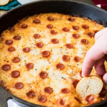 Slice of bread dipped in skillet of pizza dip