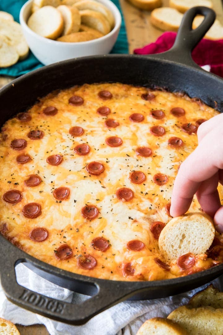 Dipping bread into a skillet of pizza dip