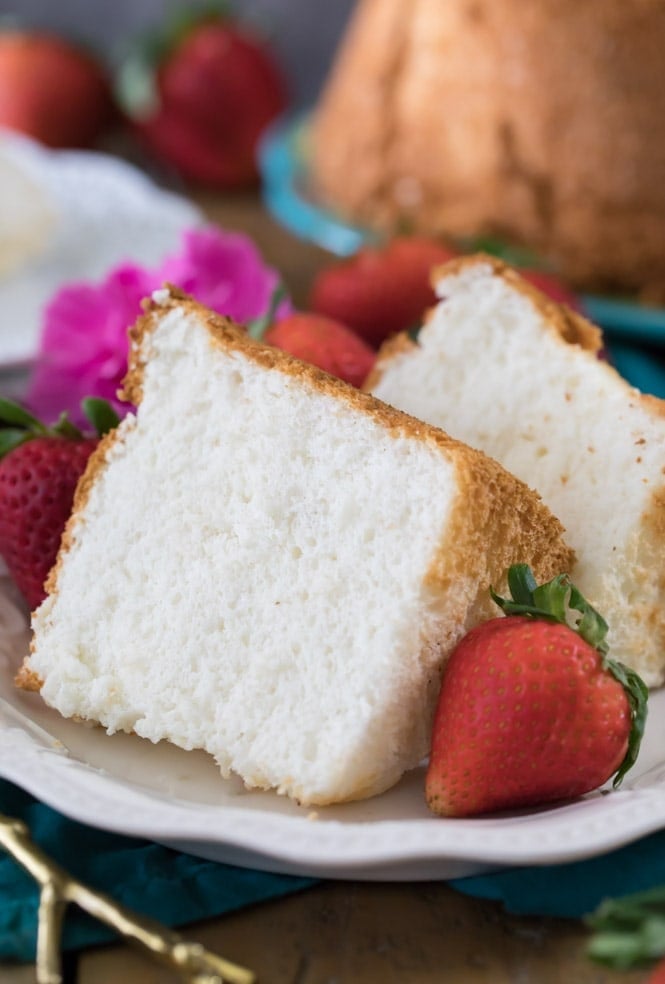 Two slices of angel food cake on white plate with strawberries