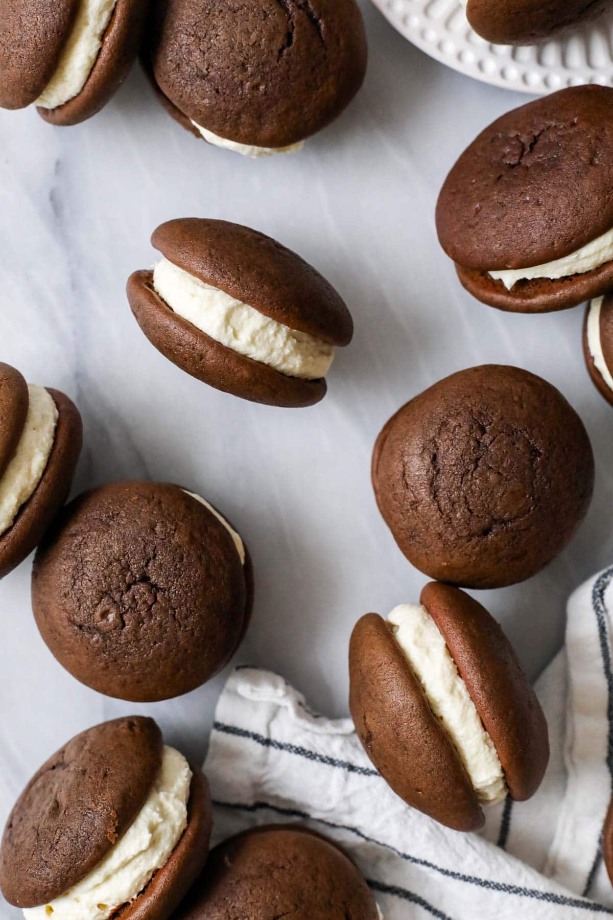 Overhead view of soft chocolate cookie sandwiches with some on their sides to show their creamy filling.