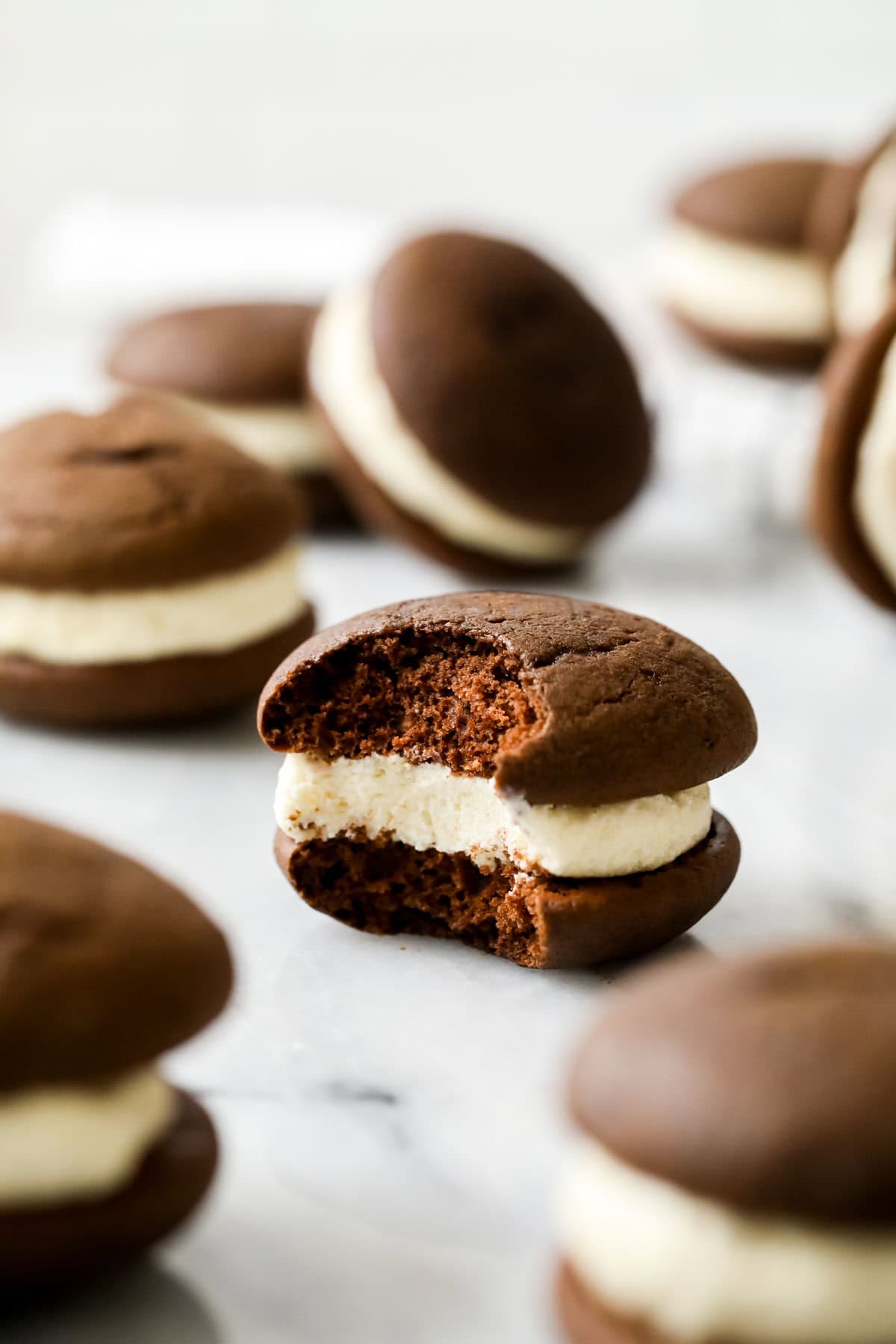 Bite missing from a chocolate gob sandwich cookie to show its cakey cookie texture and creamy filling.