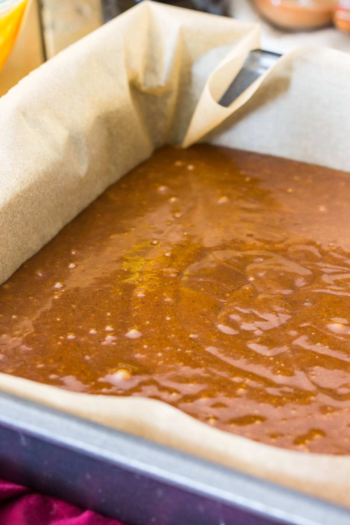 Gingerbread cake batter in metal pan that's been lined with parchment paper