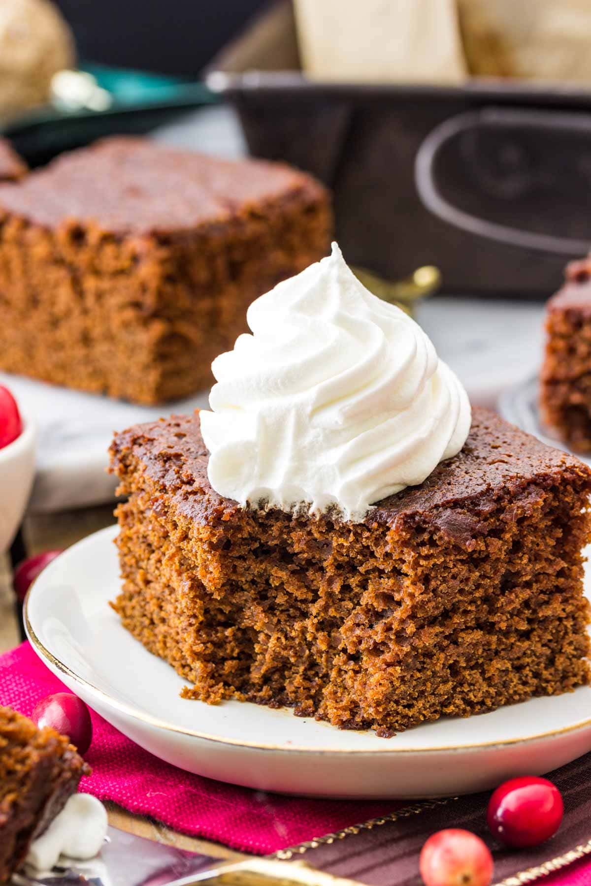 square slice of old fashioned gingrebread cake on a white plate with a bite misssing