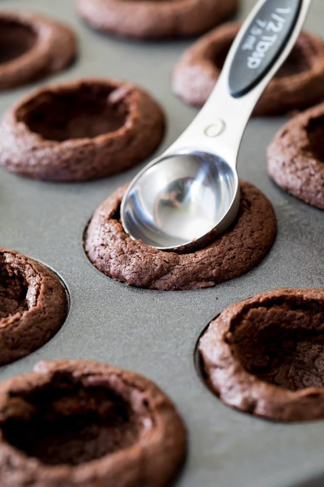 Brownies in pan with spoon pressing down centers