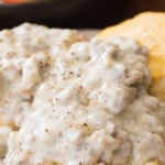 Sausage gravy on biscuits on white plate