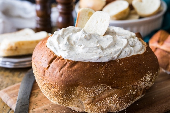 Dill dip in bread bowl on cutting board