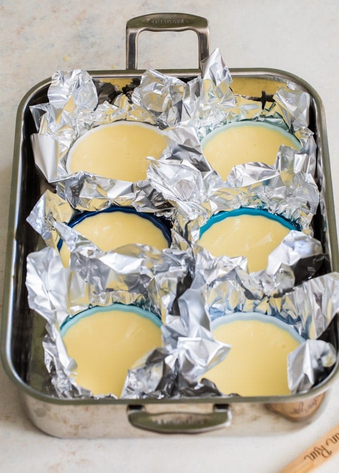 Pan full of individual creme brûlée dishes each cupped in foil