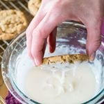 Oatmeal cookie dipped into bowl of icing