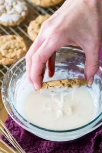 Oatmeal cookie dipped into bowl of icing