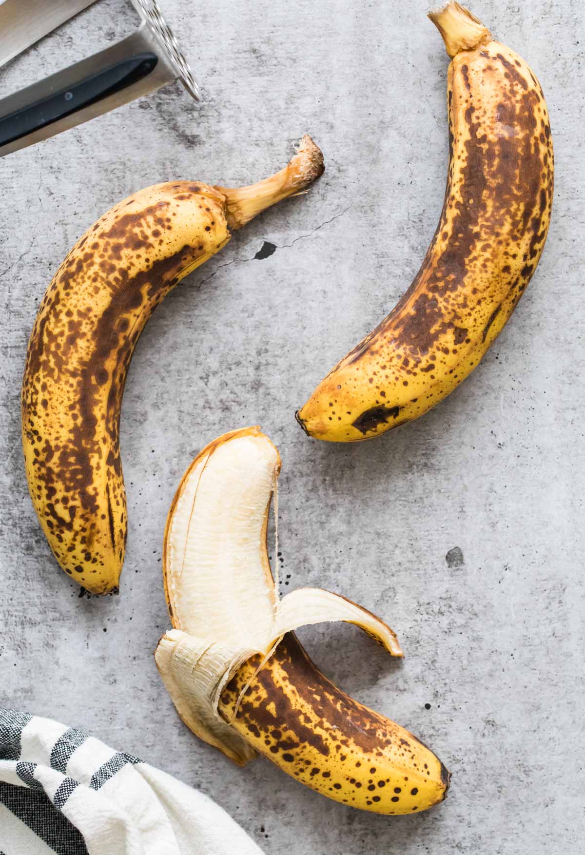 three bananas, one partially unpeeled