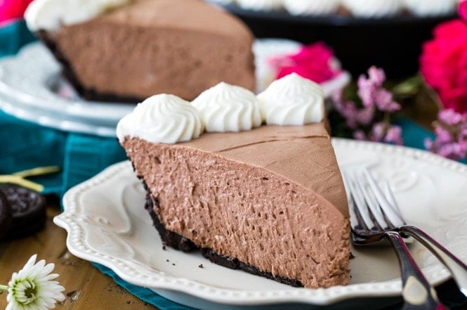 Creamy slice of chocolate icebox pie on white plate, topped with whipped cream