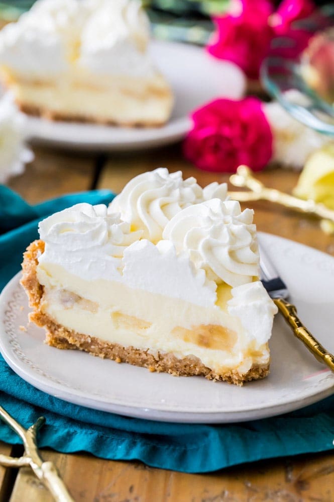 Slice of banana cream pie with whipped cream on white plate
