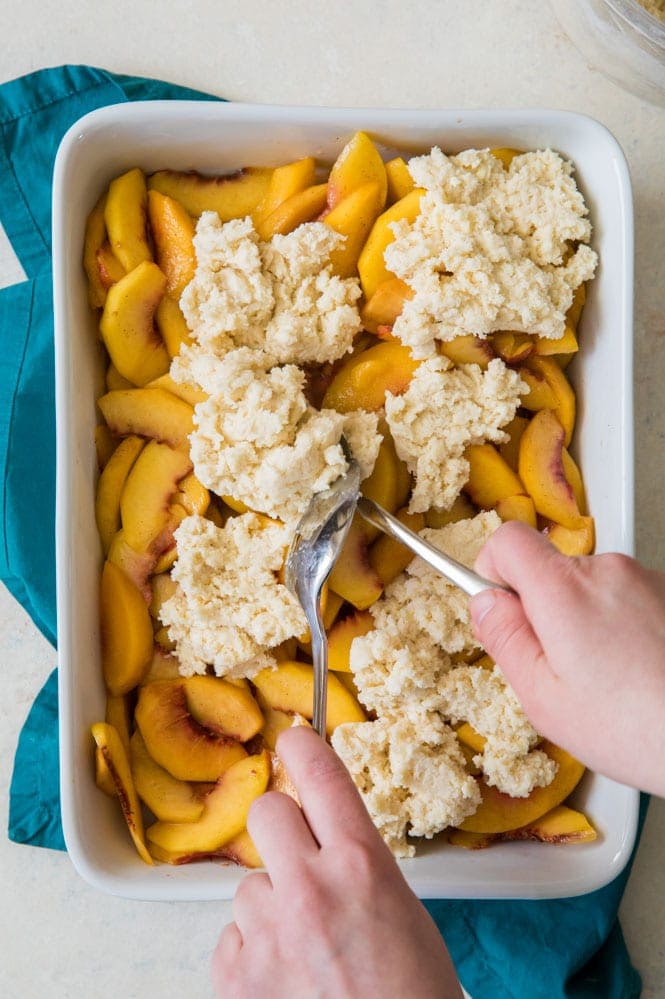 making peach cobbler: distributing batter for topping over peach mixture