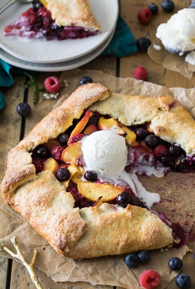 Slicing into a fruit galette that's topped with vanilla ice cream
