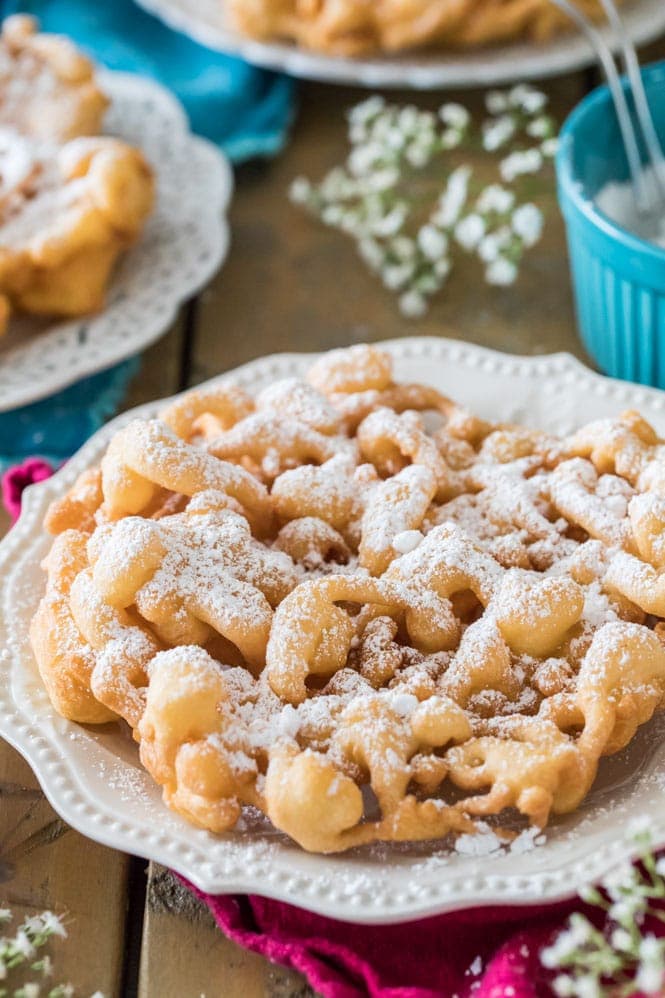 Funnel cake on white plate, dusted with powdered sugar