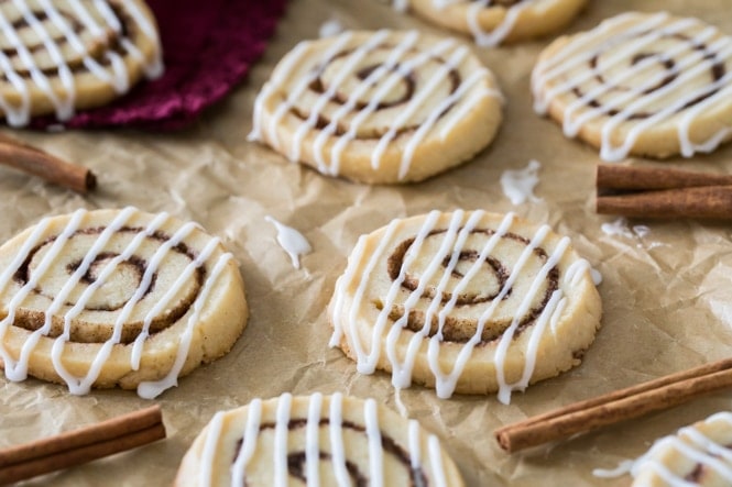 Cinnamon roll cookies on parchment paper surrounded by cinnamon sticks