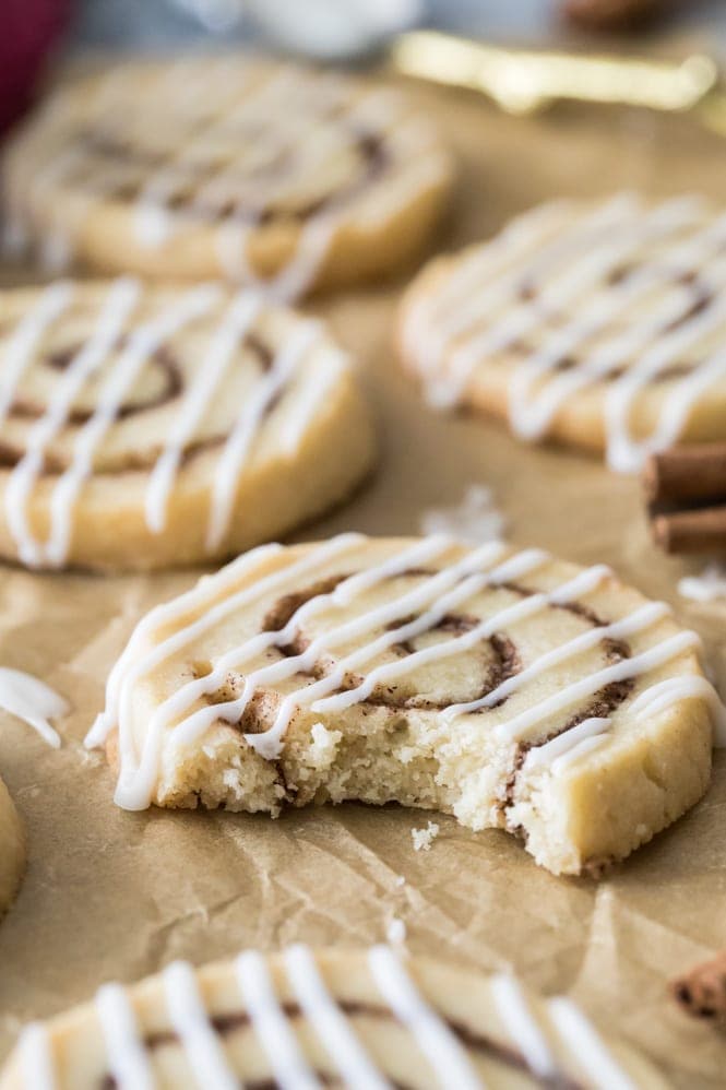 Cinnamon roll cookie on parchment paper with a bite taken out of it