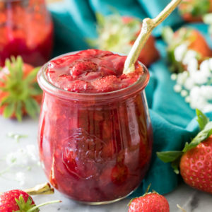 Strawberry sauce in jar with spoon on marble surface