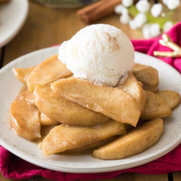 Fried apples topped with ice cream on white plate