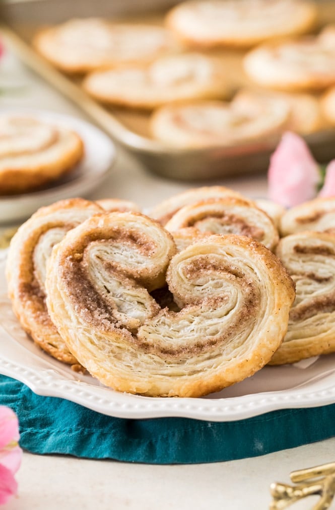 Freshly baked palmiers on a white plate, showcasing buttery flaky layers and cinnamon filling.