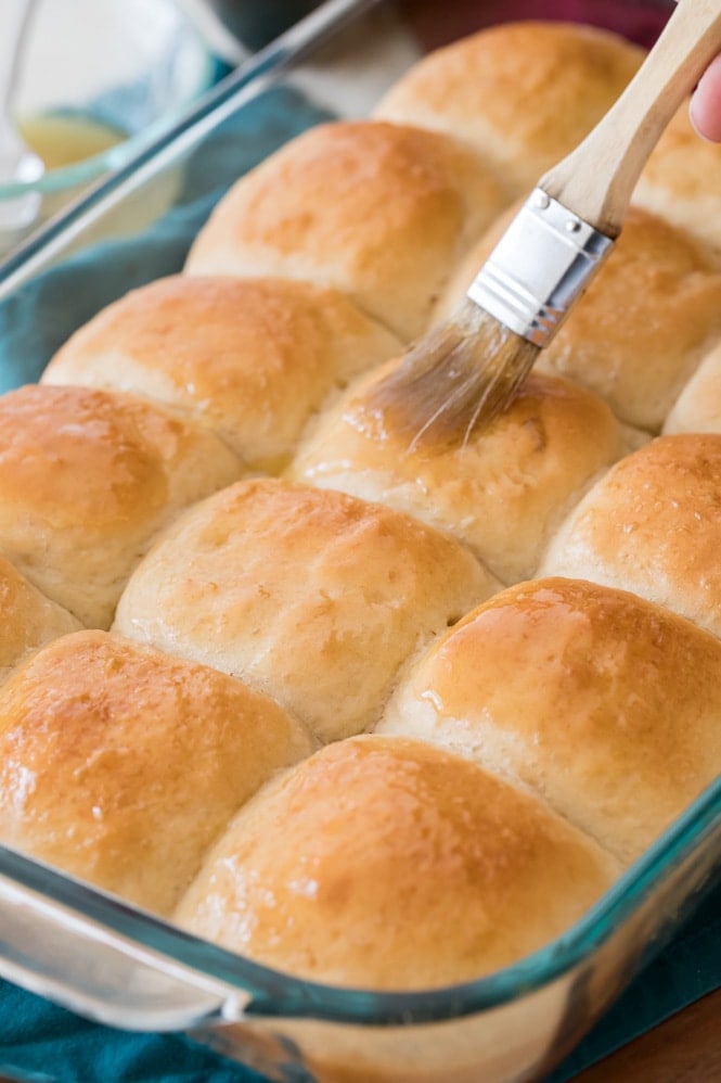 Brushing freshly baked dinner rolls with melted honey butter