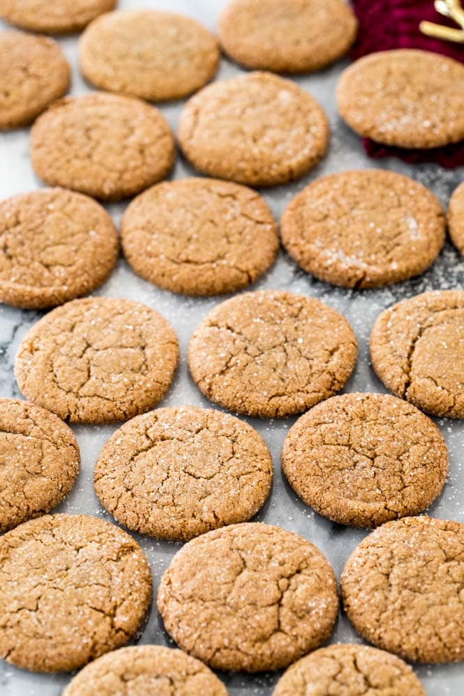 Dozens of gingersnap cookies cooling on marble board