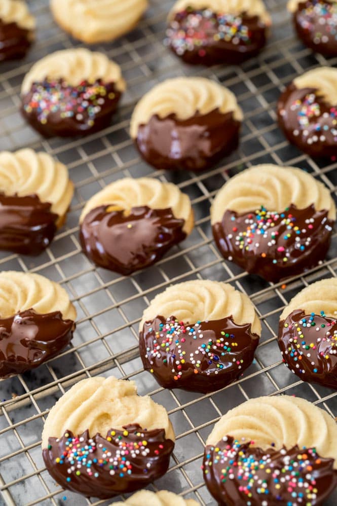 Butter cookies that have just been dipped in chocolate and sprinkled with nonpareils