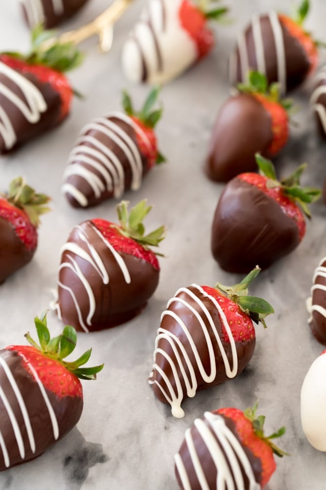 Dark chocolate covered strawberries with white chocolate drizzle on marble