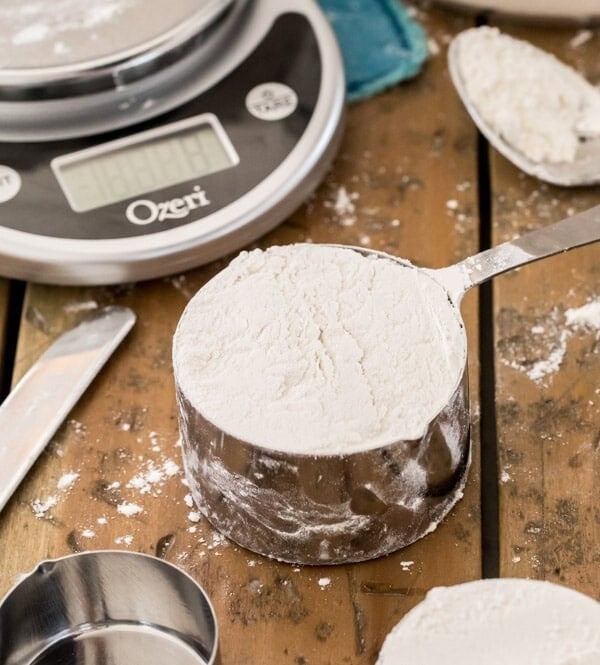 cup of flour on wood surface with scale in background