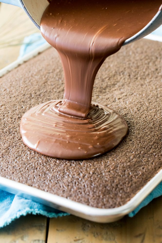Pouring the chocolate frosting over chocolate sheet cake