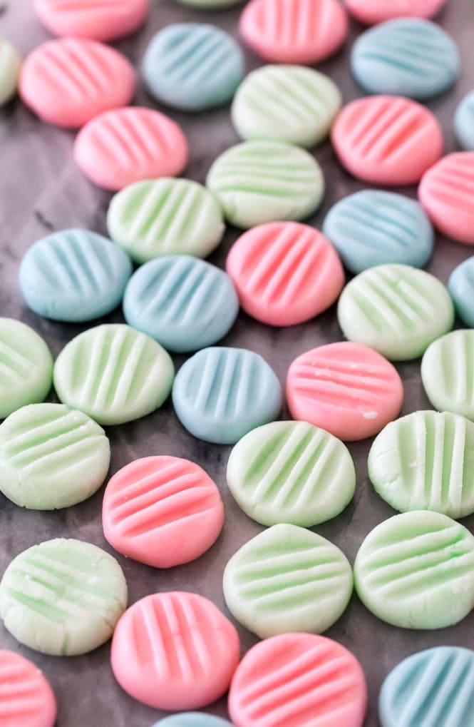 Pink, blue, and green cream cheese mints on a marble board