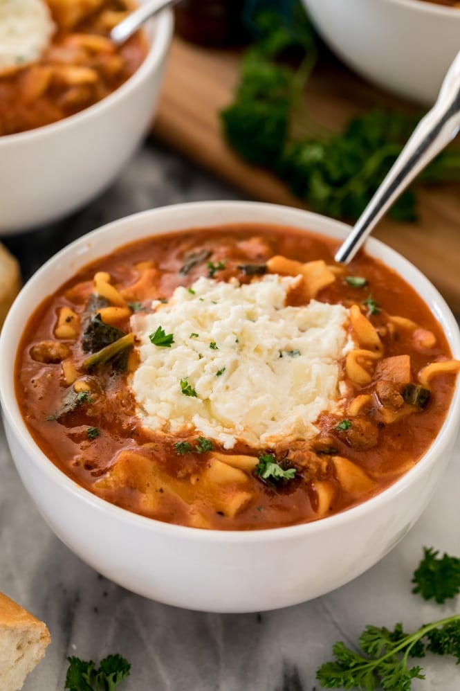 Lasagna soup recipe in a white bowl with ricotta topping