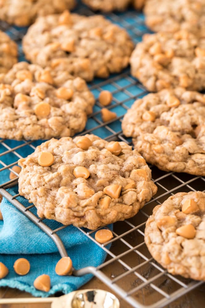 Oatmeal scotchies cooling on a gold wire wrack with a blue towel underneath