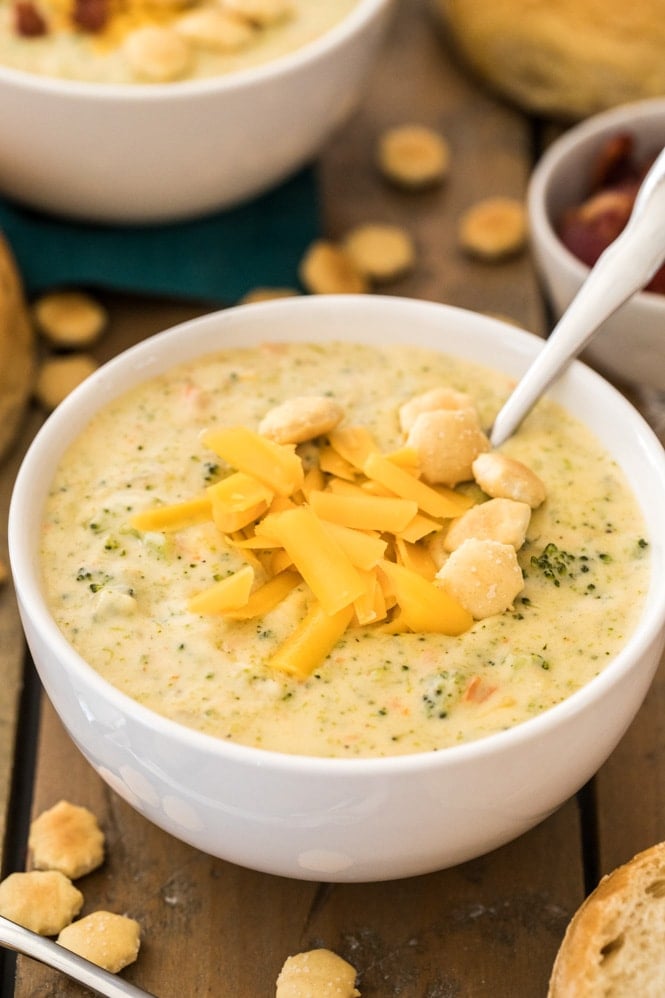 broccoli cheddar soup topped with shredded cheese and oyster crackers in a white bowl
