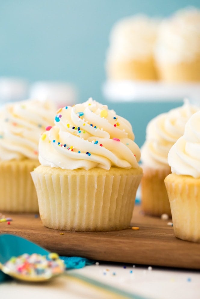 Vanilla buttercream frosting piped on a vanilla cupcake in front of a blue background