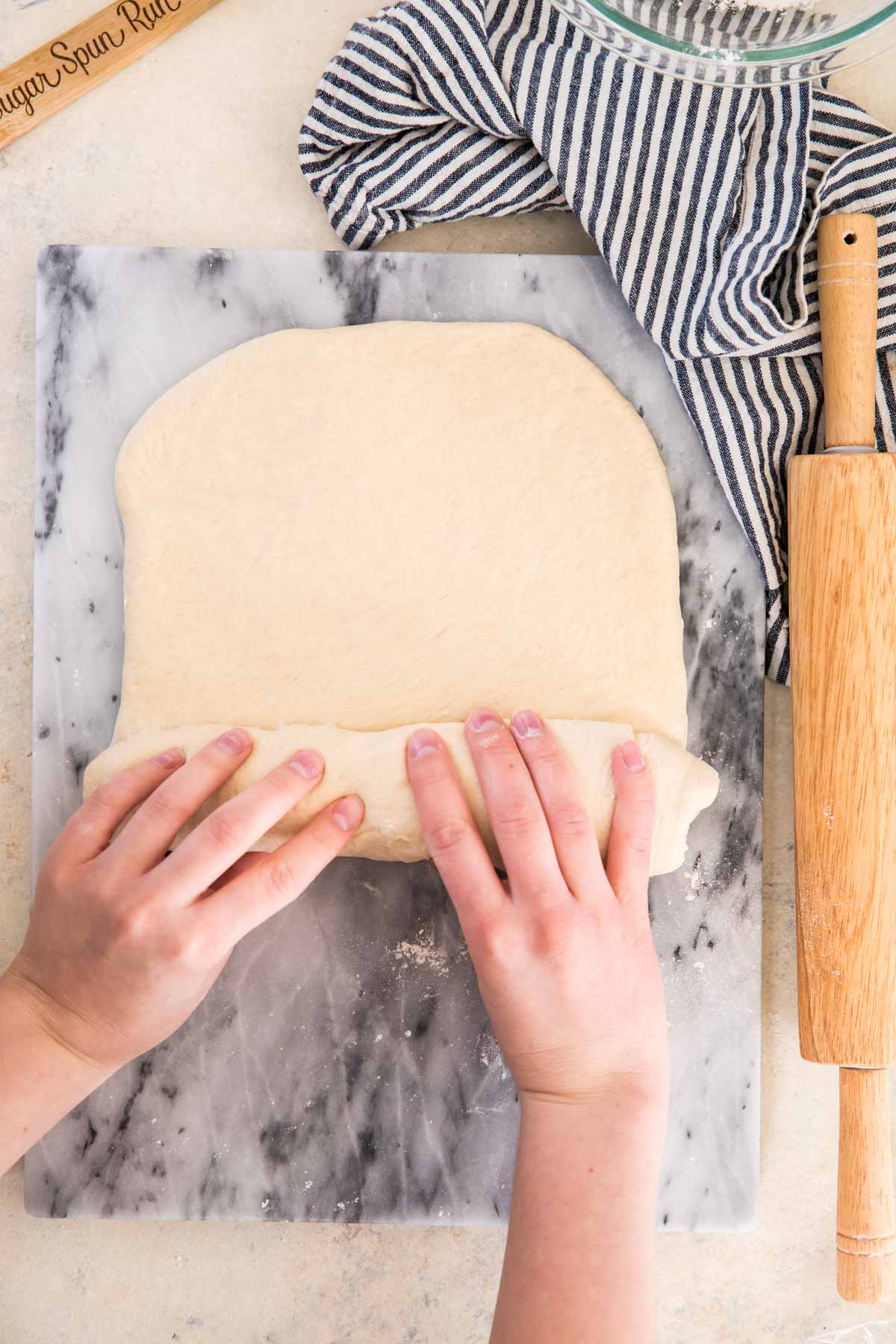 rolling dough into a loaf on a marble cutting board