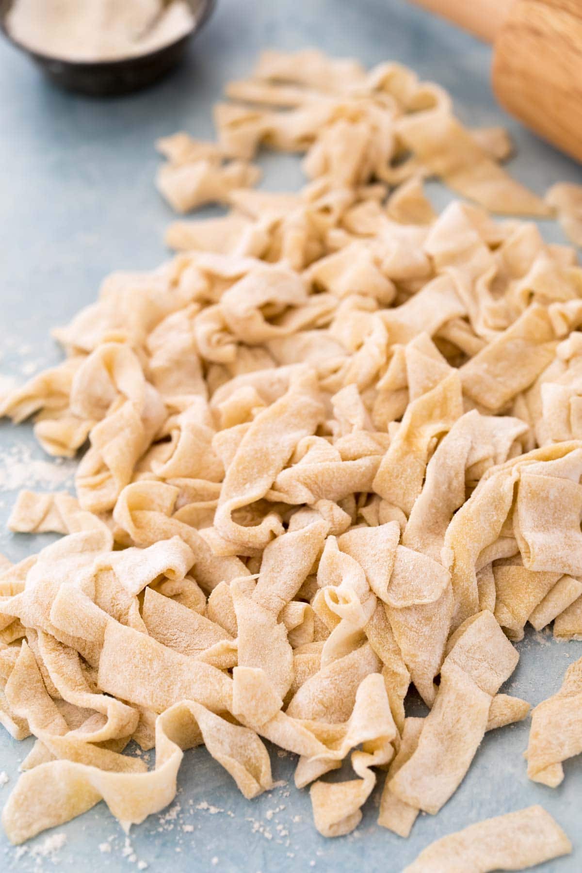 freshly cut egg noodles in a pile on blue background