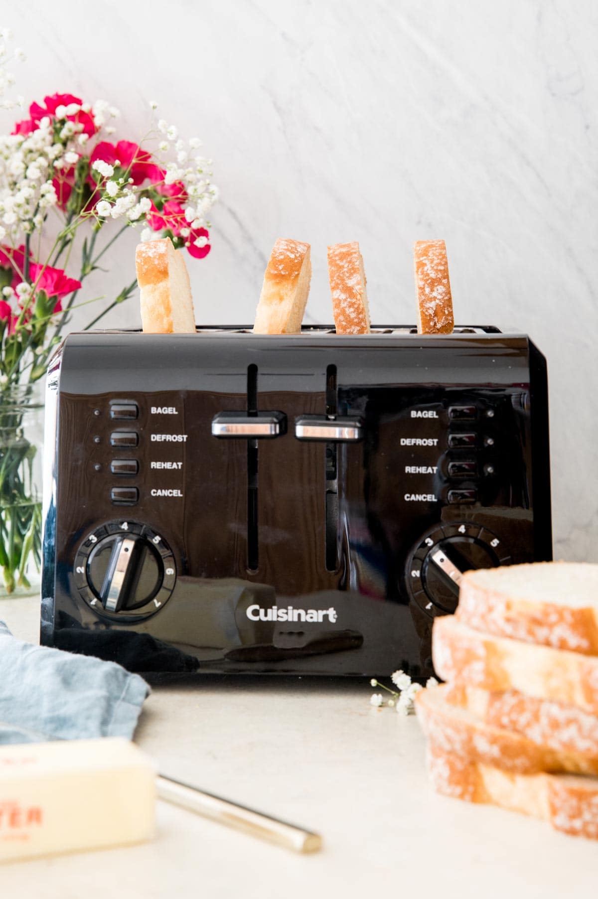 4 pieces of toast in a black toaster with pink and white flowers in the background