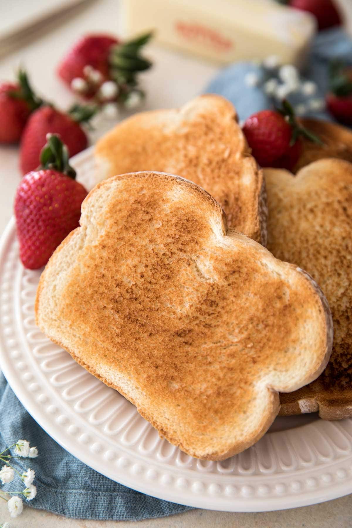 Toast on a white plate with strawberries in the background