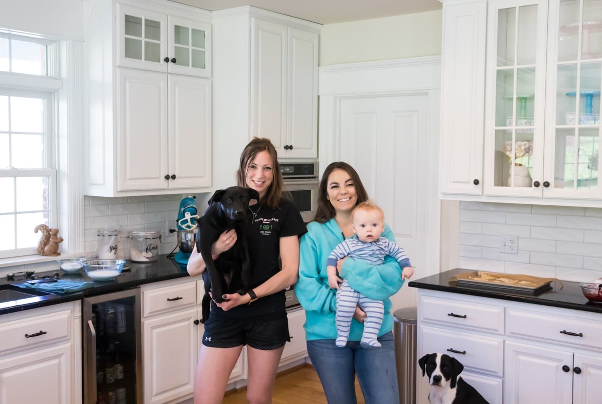 two girls, one holding a puppy and the other holding a baby