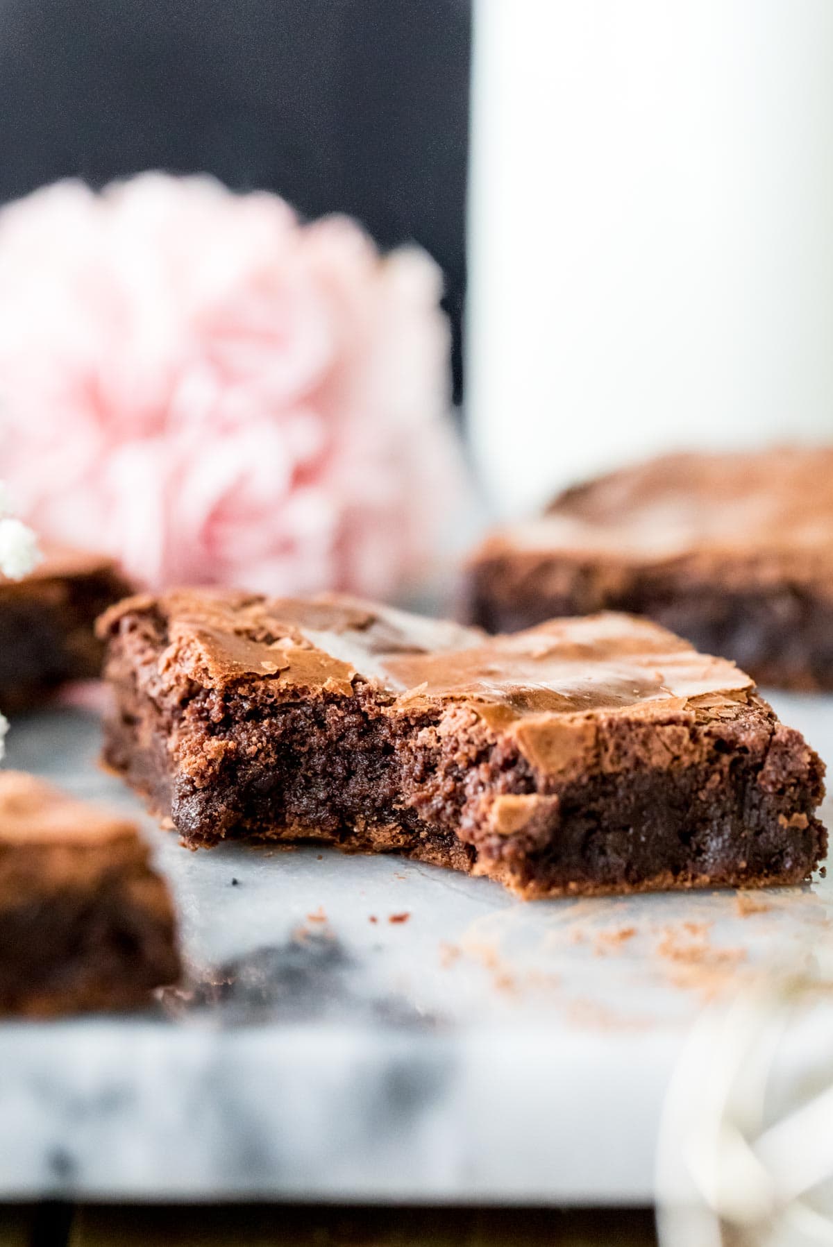 flourless brownie on marble with pink flowers in background