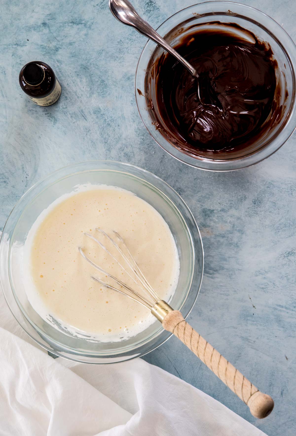 mixing batter in glass bowls, egg mixture in lower bowl, melted chocolate in upper