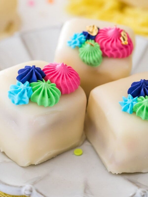 Petit fours on white plate with colorful frosting
