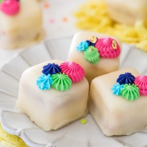 Petit fours on white plate with colorful frosting