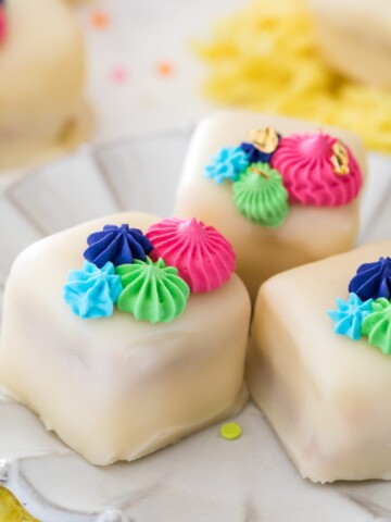Petit fours on white plate with colorful frosting