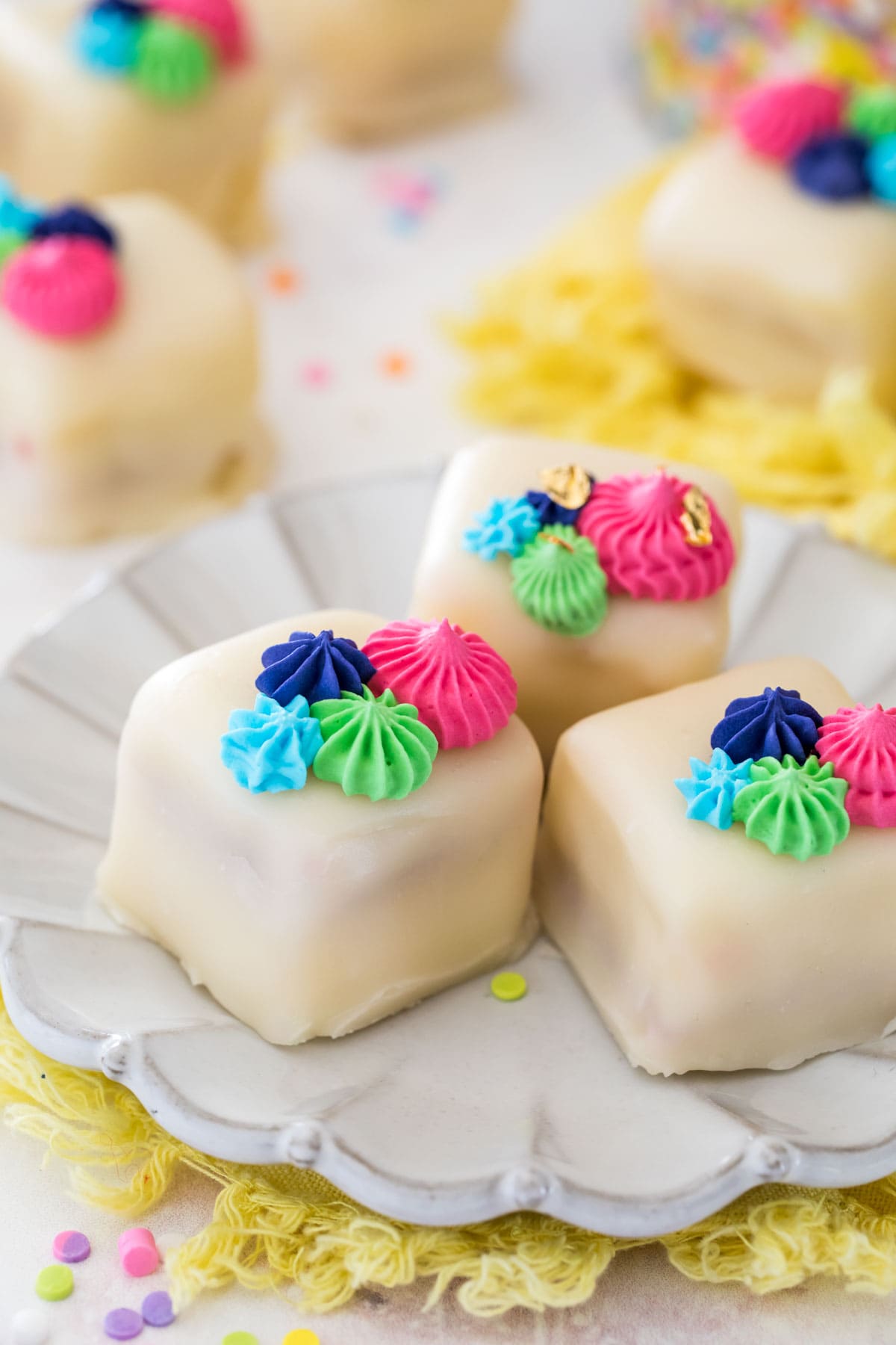 Petit fours on white plate with colorful frosting